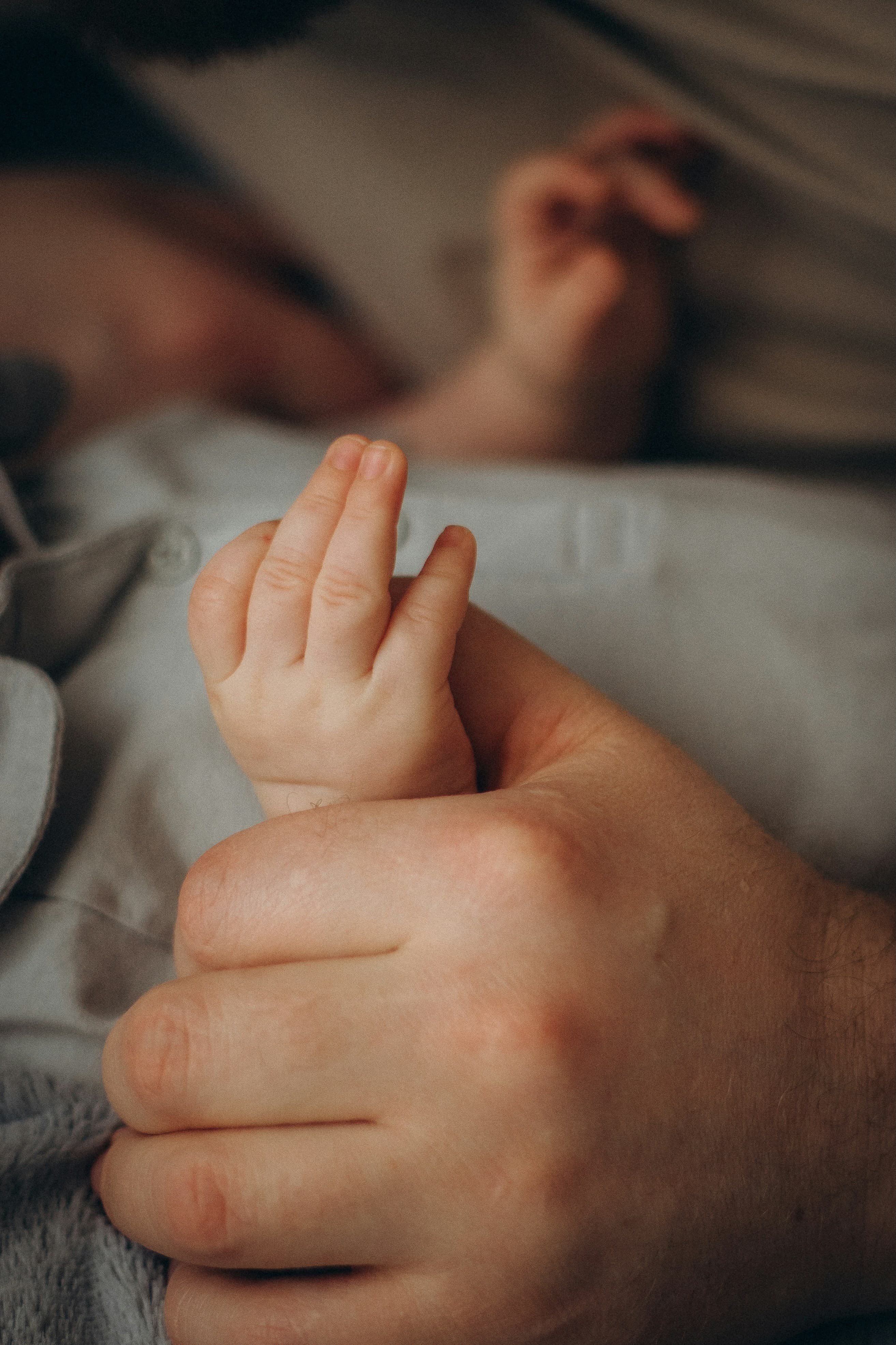 A baby's hand holding a parent's finger.