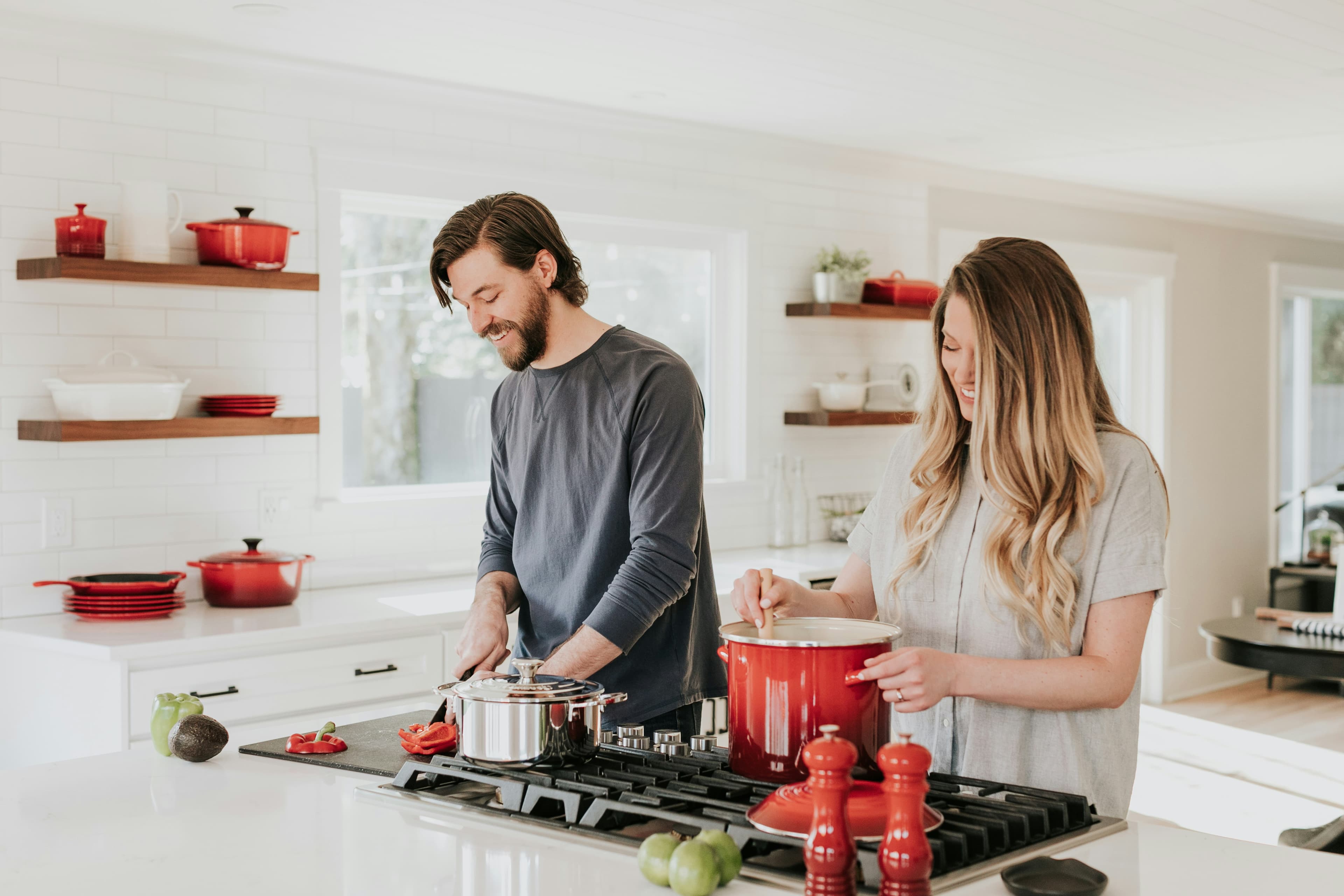 A couple laughing as they cook dinner together in their kitchen.