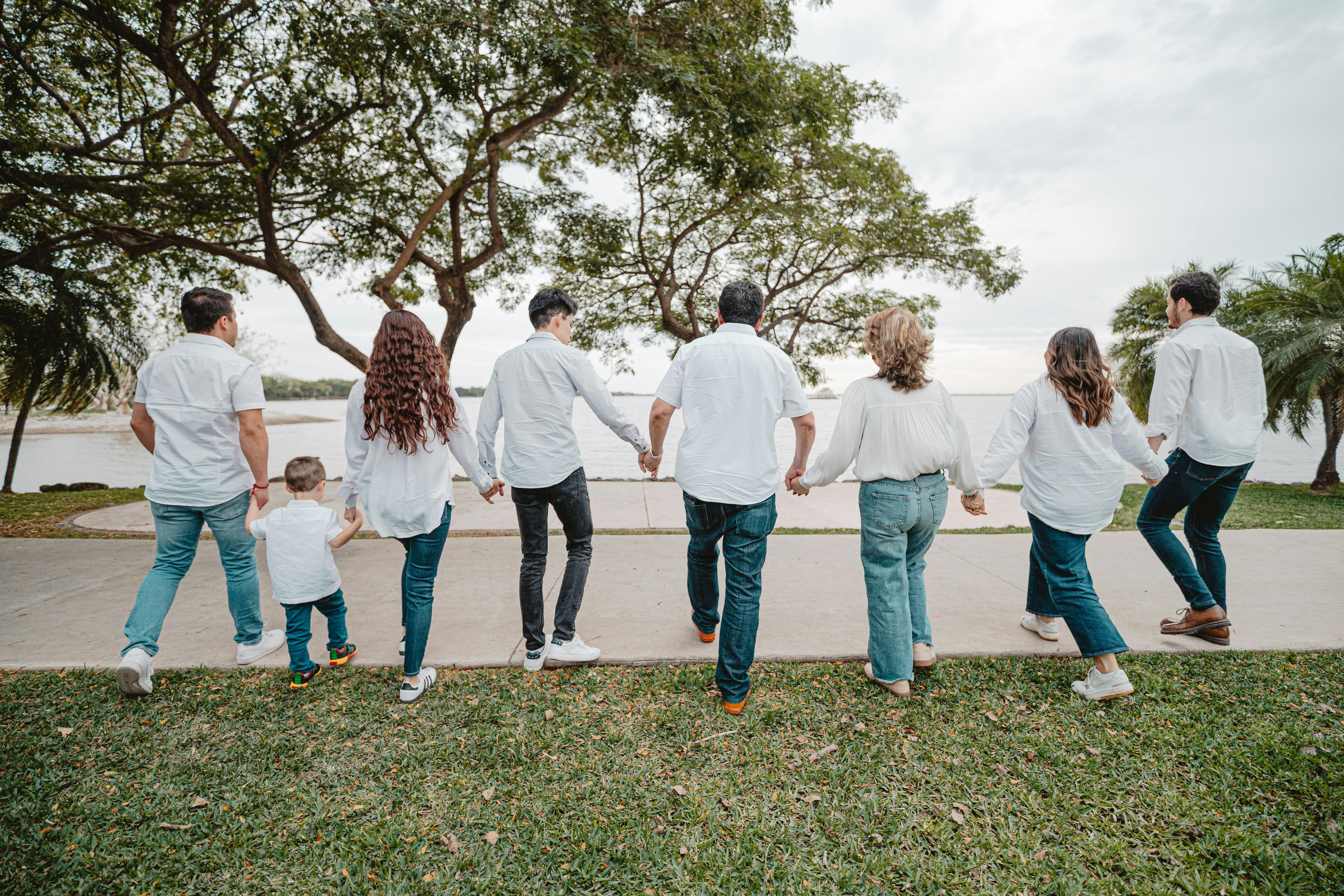 A big family of all ages walking hand in hand along a lakeside path.