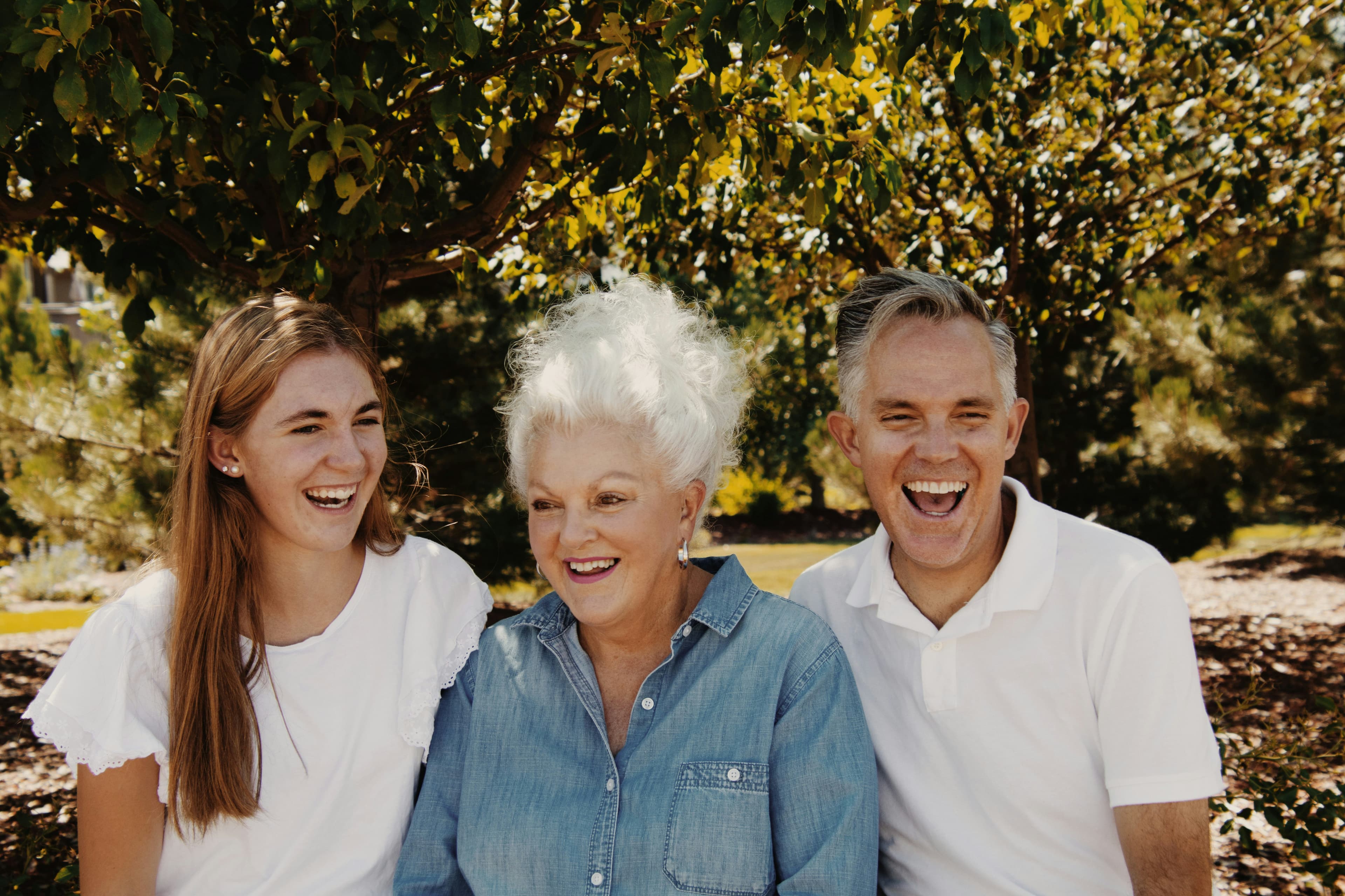 A grandmother laughing with her grown son and granddaughter.