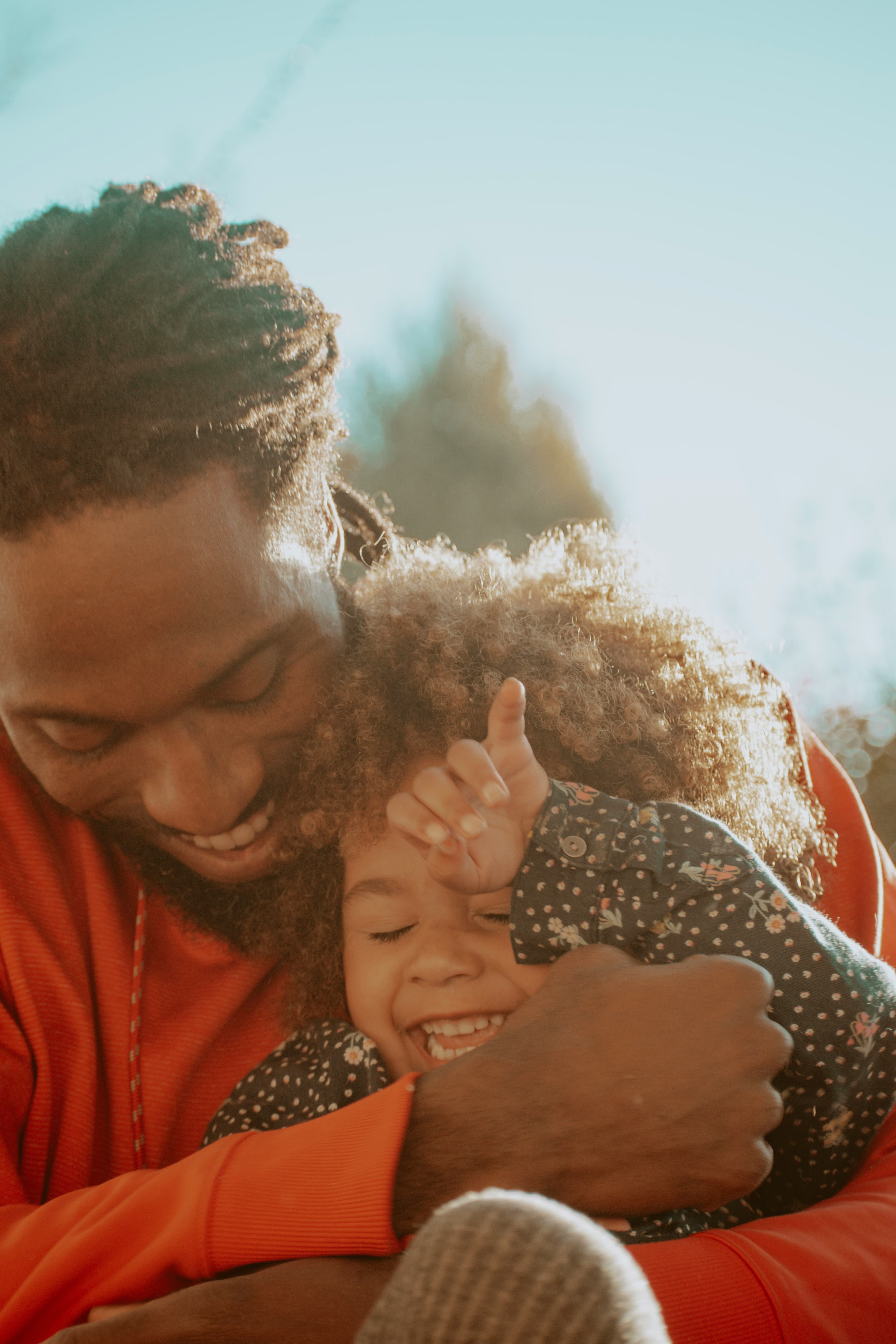 A father hugging his laughing daughter close.