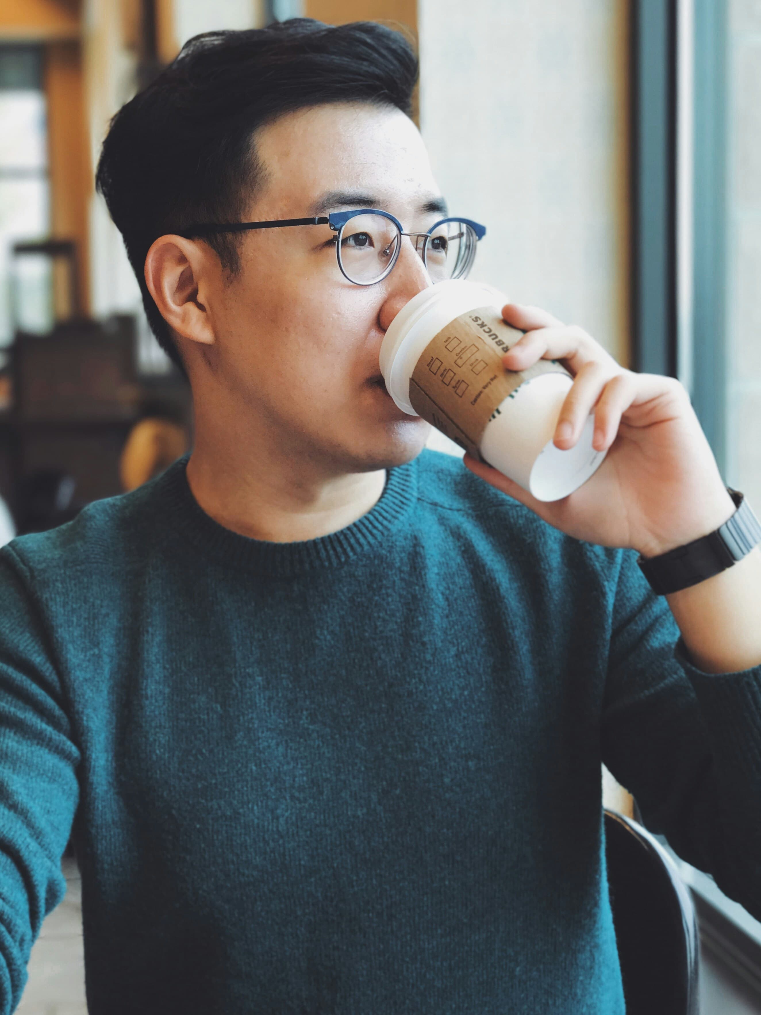 A man drinking coffee and looking out of a window.
